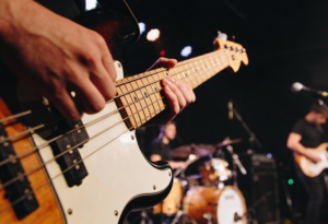 Junger Mann spielt Bassgitarre mit einer Hand