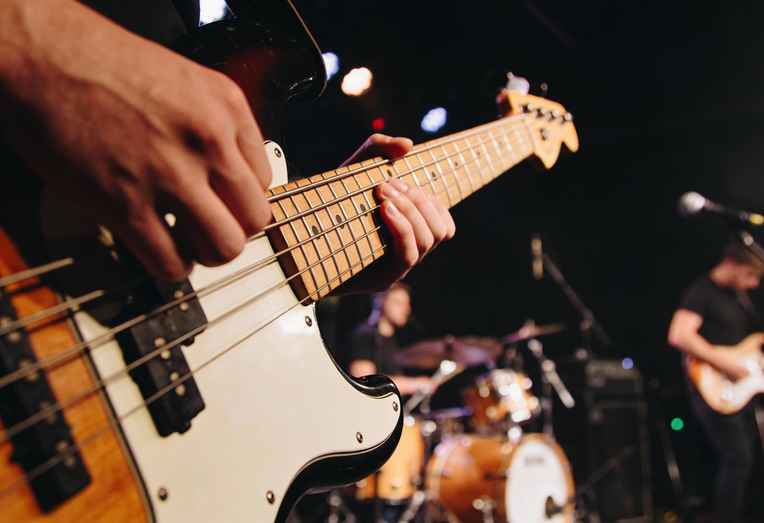 Junger Mann spielt Bassgitarre mit einer Hand