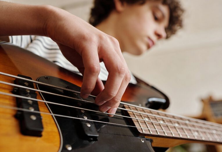 Junger Mann spielt Bassgitarre mit einer Hand