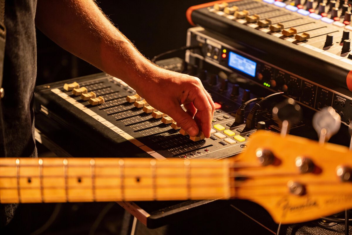 Hand eines Bassisten regelt die Lautstärke auf einem Mischpult