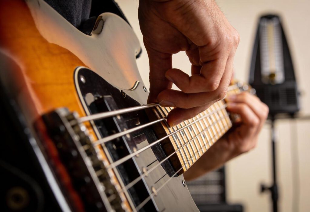 Nahaufnahme einer Hand, die über die Saiten eines Basses spielt