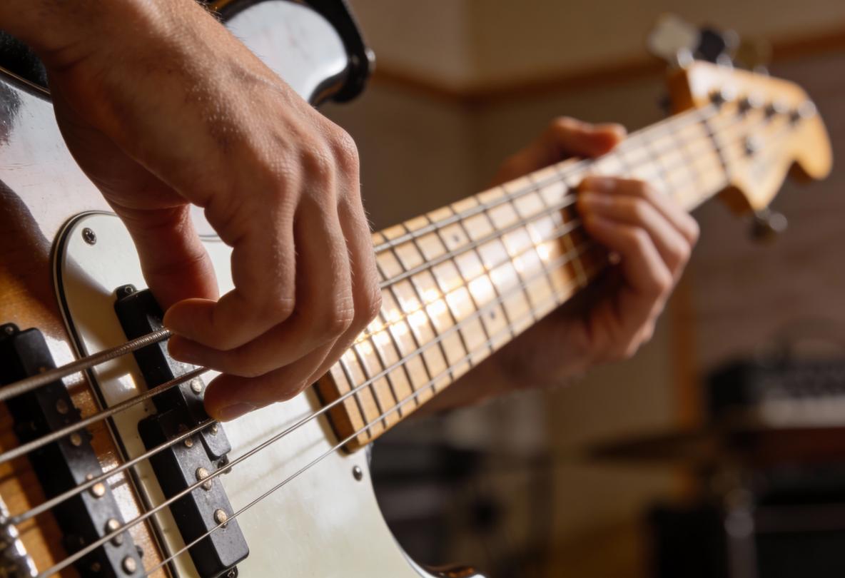 Nahaufnahme einer Hand, die eine Bass-Saite zupft