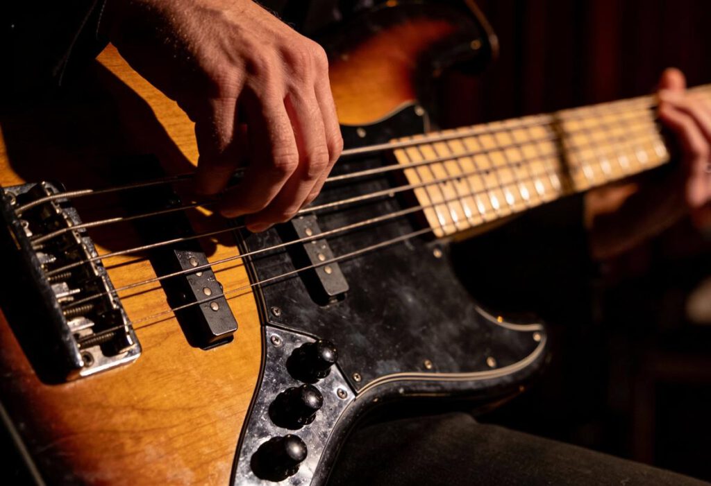 Nahaufnahme eines Bassisten, der auf einer E-Bass-Saite spielt