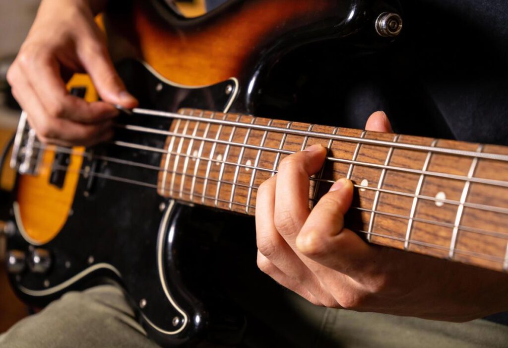 Nahaufnahme einer Hand, die eine Bassgitarre bespielt.