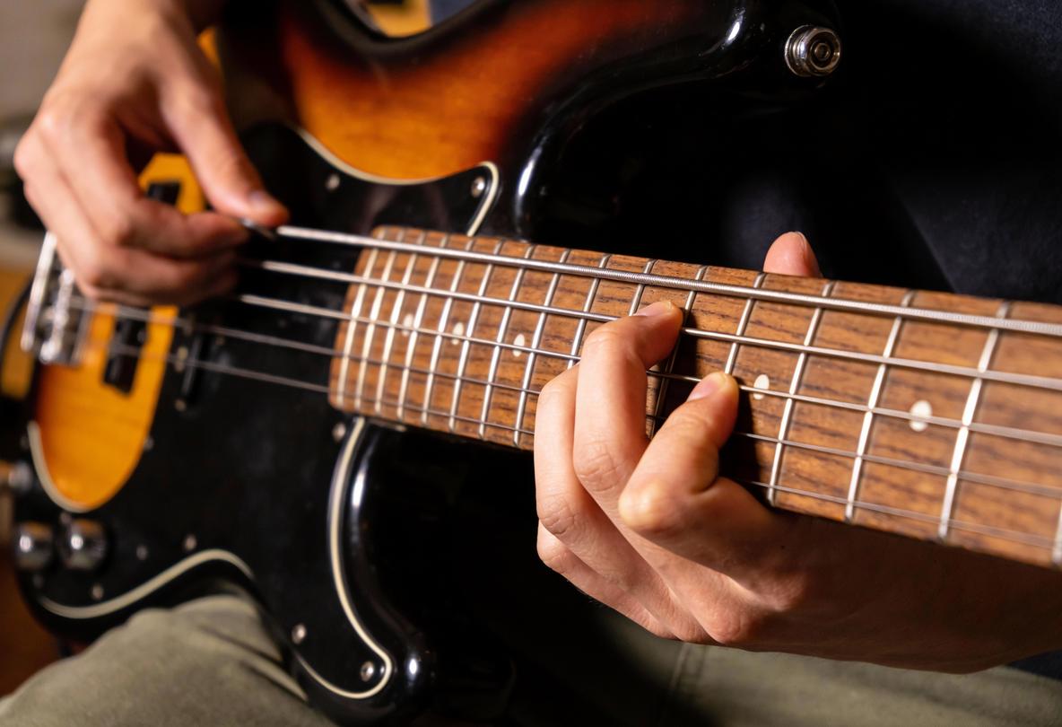 Nahaufnahme einer Hand, die eine Bassgitarre bespielt.