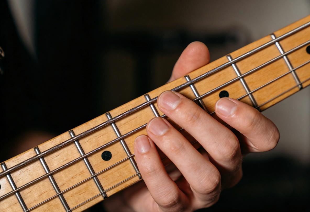 Hand spielt auf den Saiten einer E-Bassgitarre