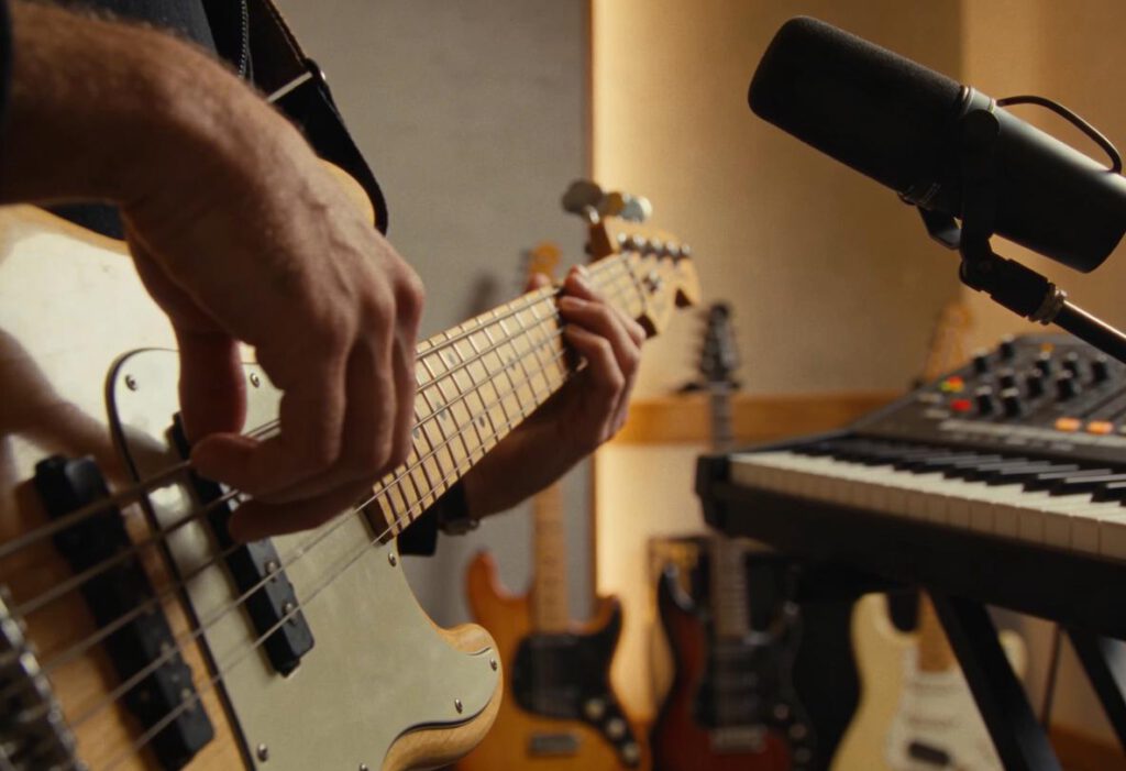 Nahaufnahme von einem Bassisten, der im Studio E-Gitarre spielt.