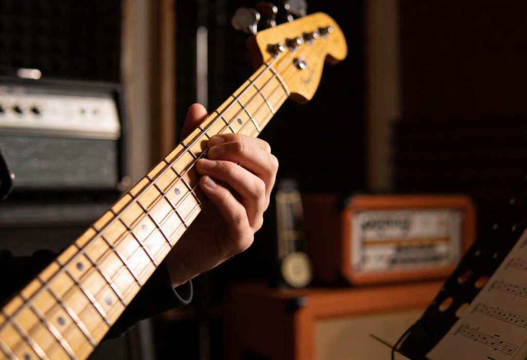 Eine Hand spielt eine Bassgitarre in einem Studio.