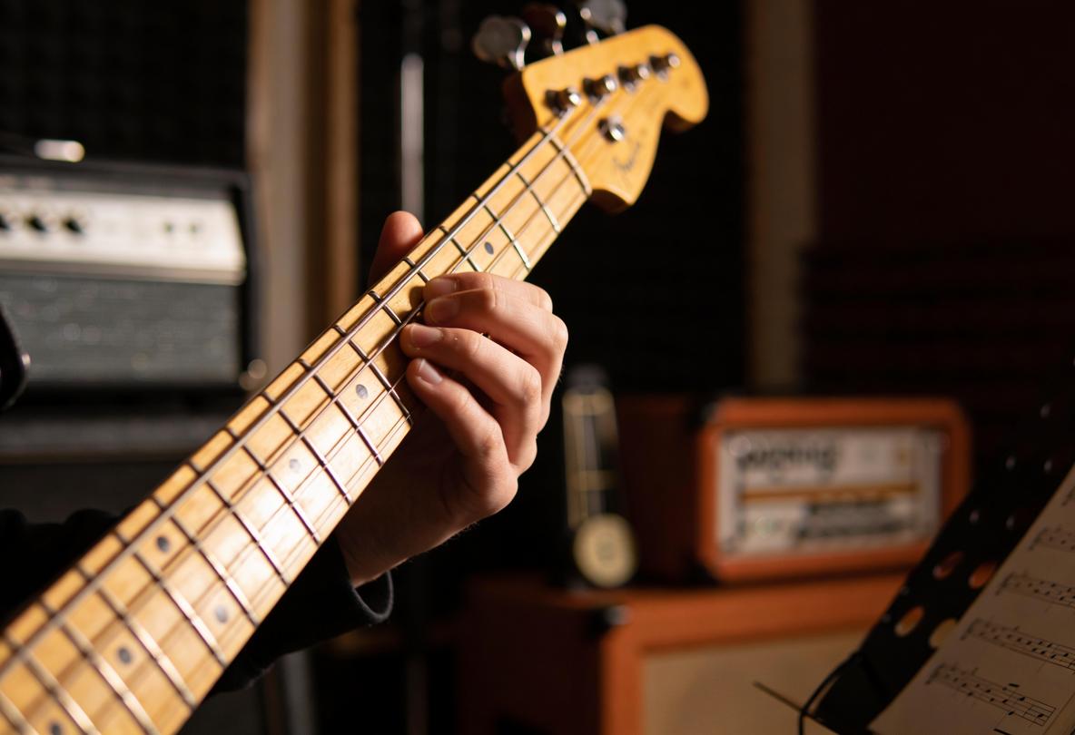 Eine Hand spielt eine Bassgitarre in einem Studio.