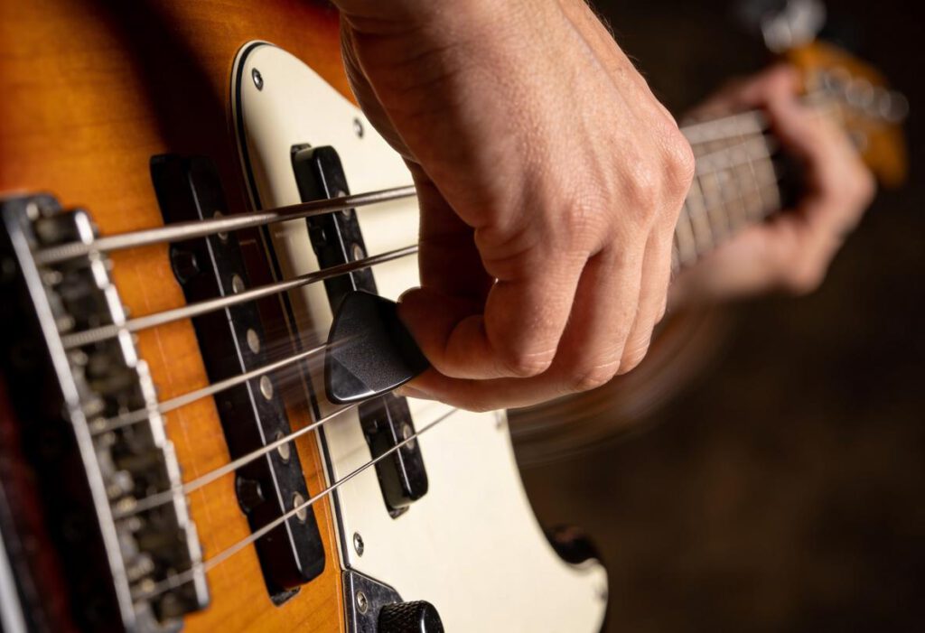 Ein Musiker spielt mit einem Plektrum Bassgitarre