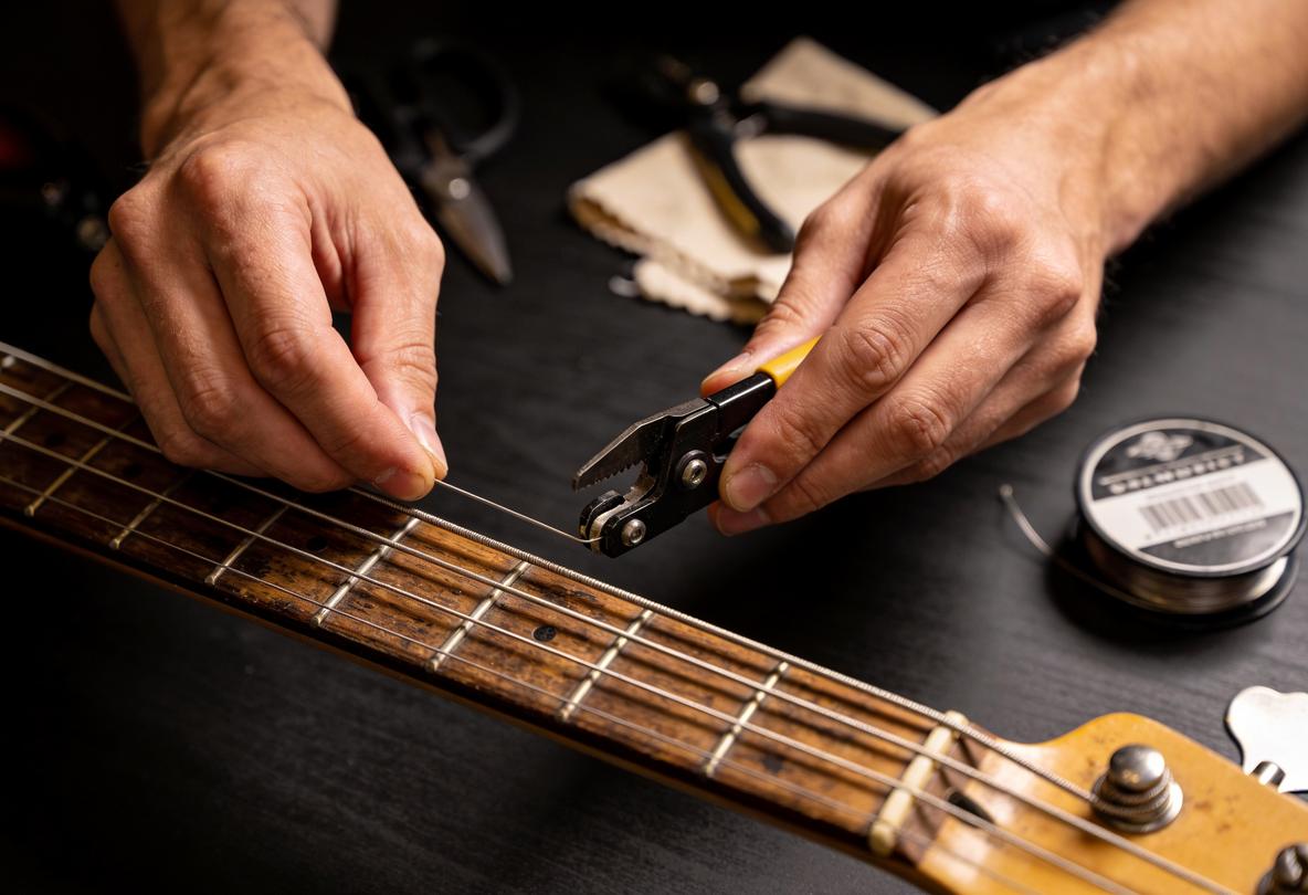 Händewechsel einer Bass-Saite mit Zange auf einem Gitarrenhals