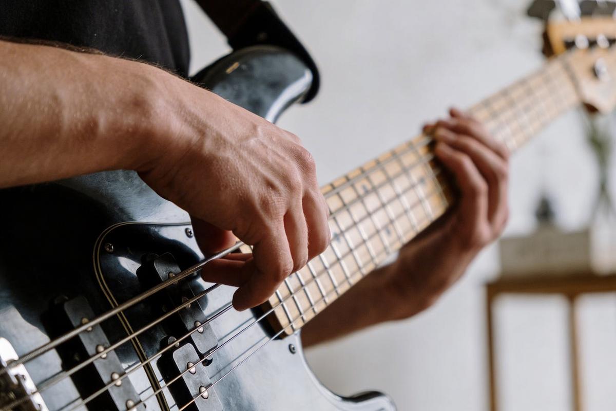 Nahaufnahme einer Hand, die die Saiten eines Basses zupft