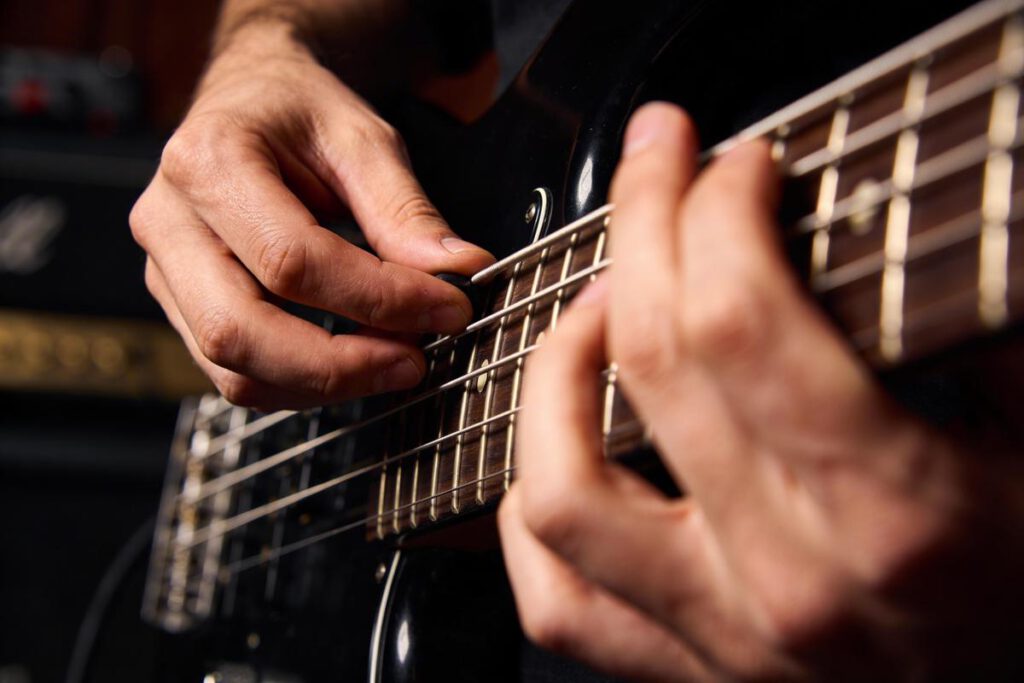 Nahaufnahme von Händen, die auf einer Bassgitarre spielen.