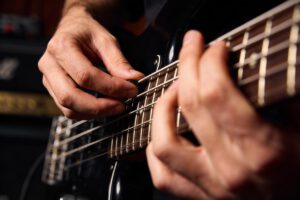 Nahaufnahme von Händen, die auf einer Bassgitarre spielen.