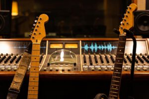 Zwei Gitarren stehen vor einer Mischkonsole im Tonstudio.