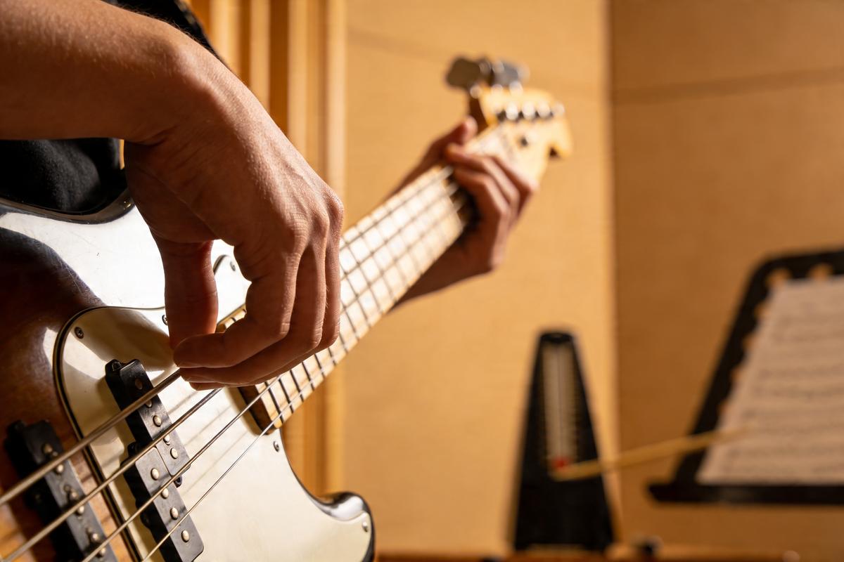 Ein Musiker spielt einen Bass mit einer Hand auf den Saiten und der anderen bereit zum Daumenanschlag.