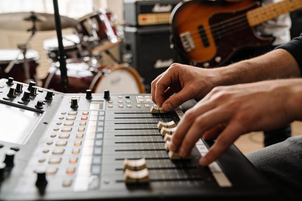 Ein Musiker justiert die Klangregler eines Mischpults im Tonstudio.