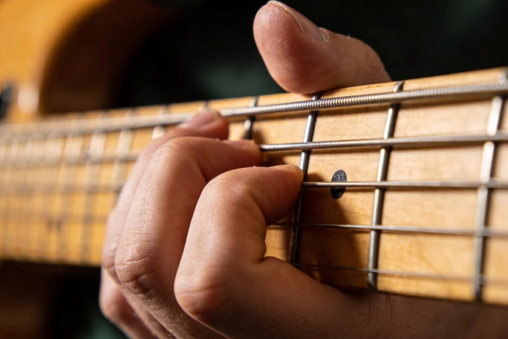 Nahaufnahme einer Hand, die eine Bassgitarre spielt