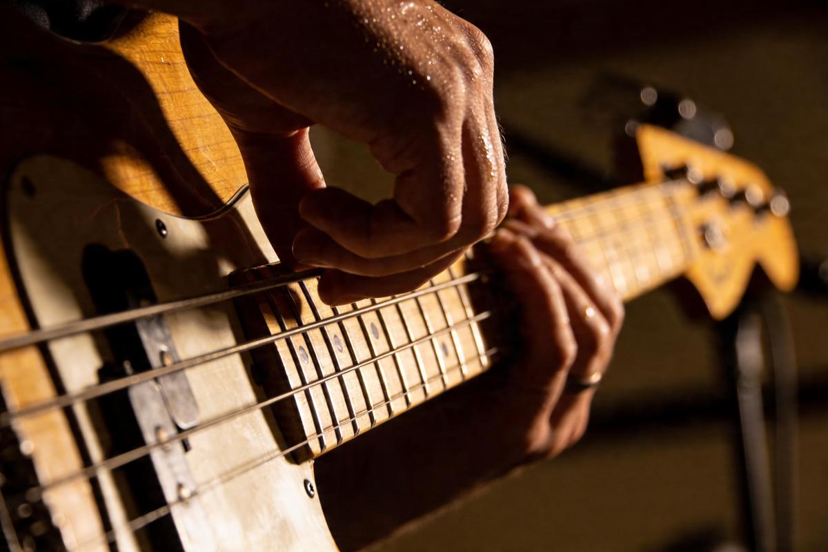Hände, die eine Bassgitarre spielen, mit Fokus auf die Saiten