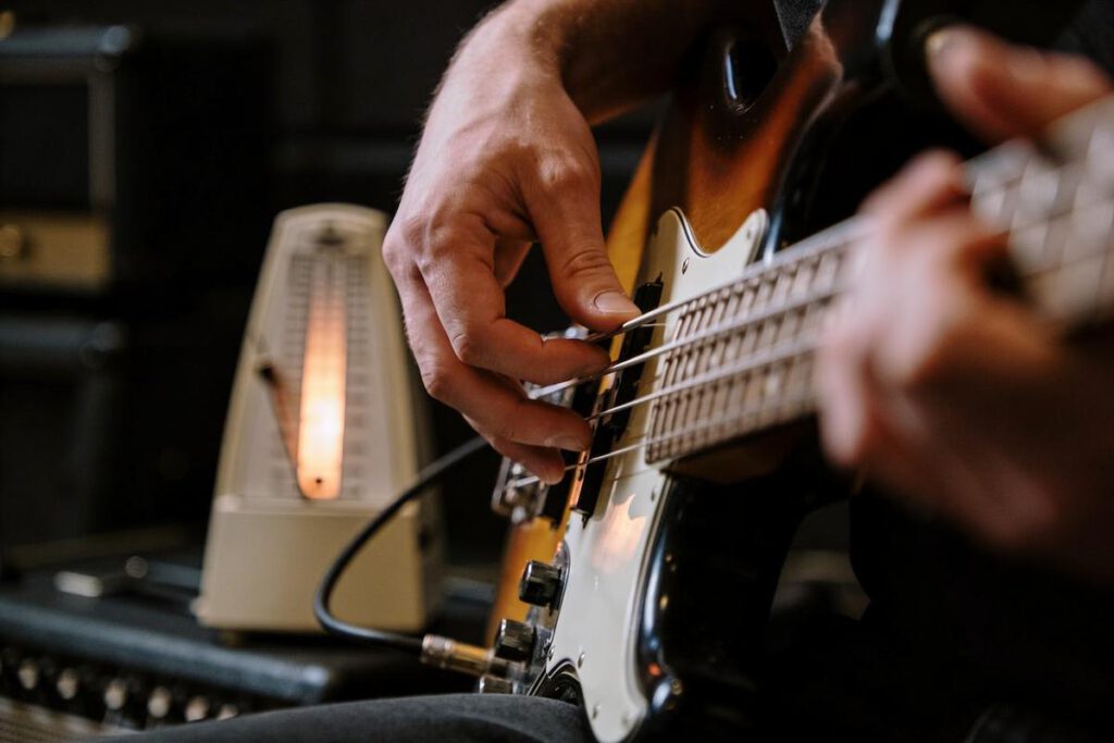 Ein Bassist spielt seinen Bassgitarre mit einem Metronom im Hintergrund.