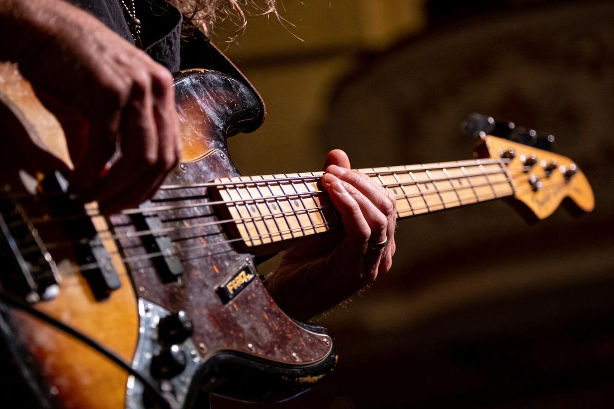 Nahaufnahme eines Bassisten, der mit seinen Händen eine E-Gitarre spielt.