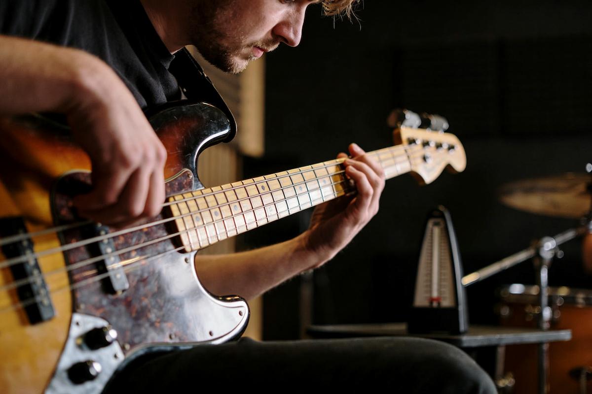 Ein Bassist spielt konzentriert auf seinem E-Bass im Proberaum.