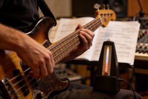 Nahaufnahme eines Spielers, der einen Bass mit einem Metronom übt.