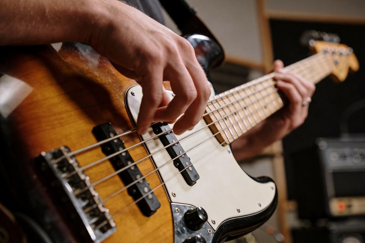 Nahaufnahme eines Bassisten, der eine E-Bass-Saite zupft.