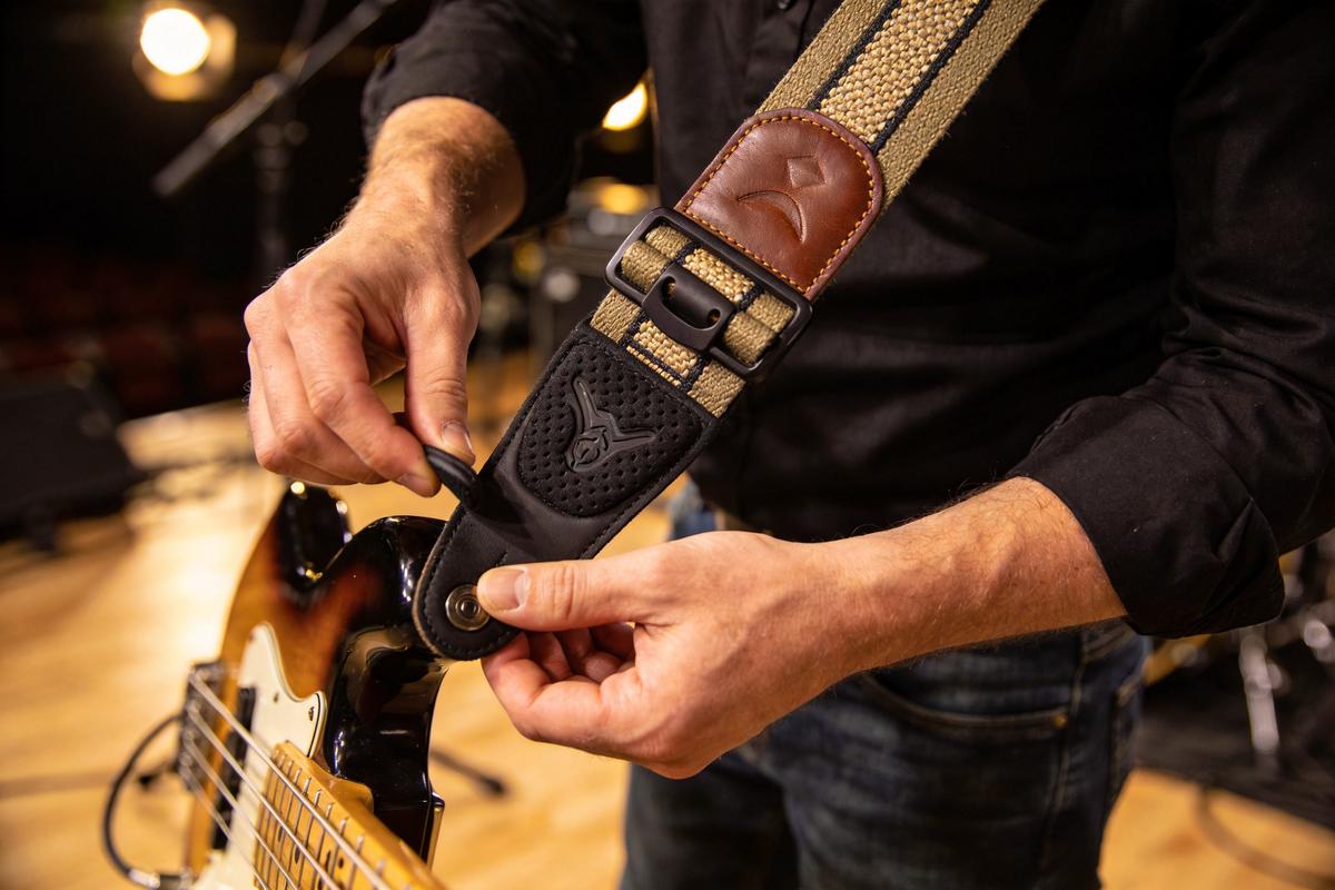 Ein Bassist befestigt einen verstellbaren Gitarrengurt an seiner E-Gitarre