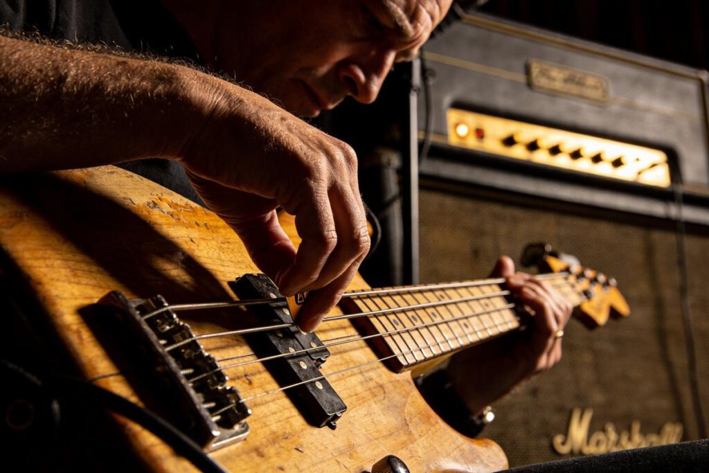 Ein Bassist zupft die Saiten eines Vintage-Bassgitarrens