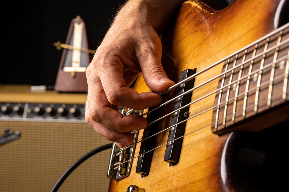 Ein Bassist spielt mit einer Hand die Saiten eines elektrischen Basses.