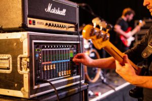 Ein Bassist passt das Mischpult während eines Live-Auftritts an.