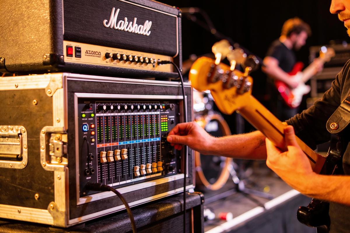 Ein Bassist passt das Mischpult während eines Live-Auftritts an.