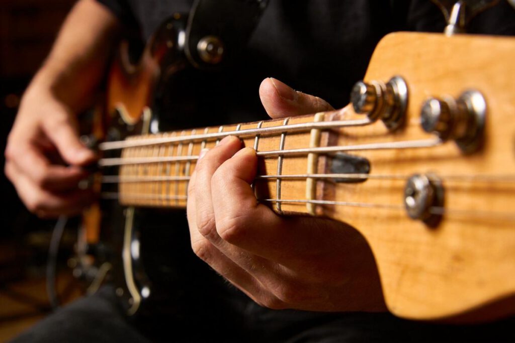 Nahaufnahme einer Hand, die auf den Saiten eines Basses spielt.
