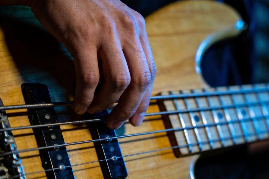 Nahaufnahme einer Hand, die die Saiten eines Basses greift