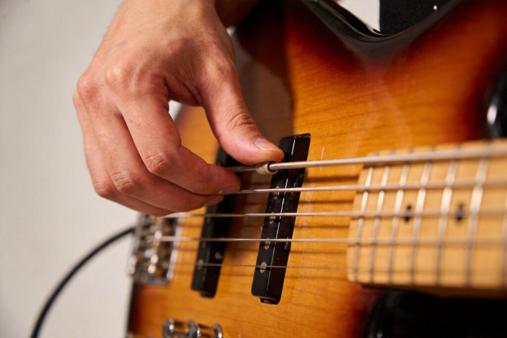 Eine Hand wechselt die Saiten an einem Bass.