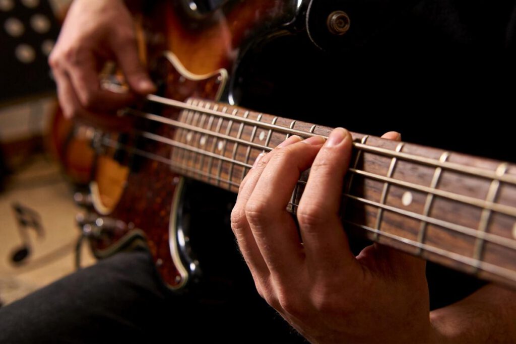 Nahaufnahme einer Hand, die auf einem Bassgitarre spielt.